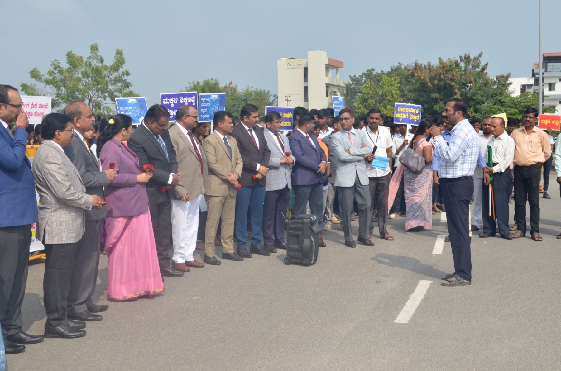 District officials lined up outdoors holding roses