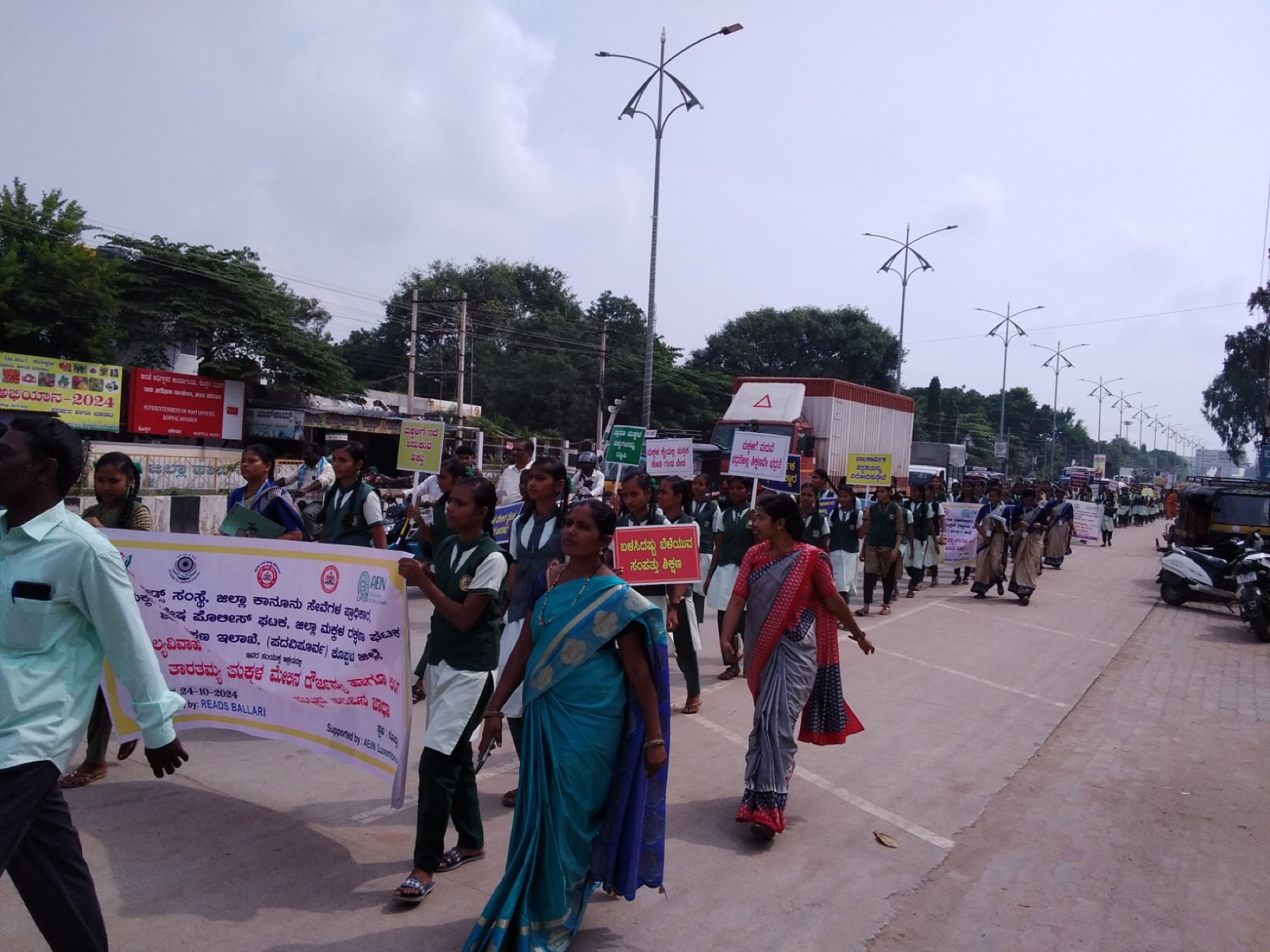 School students marching along a highway with placards in Koppal