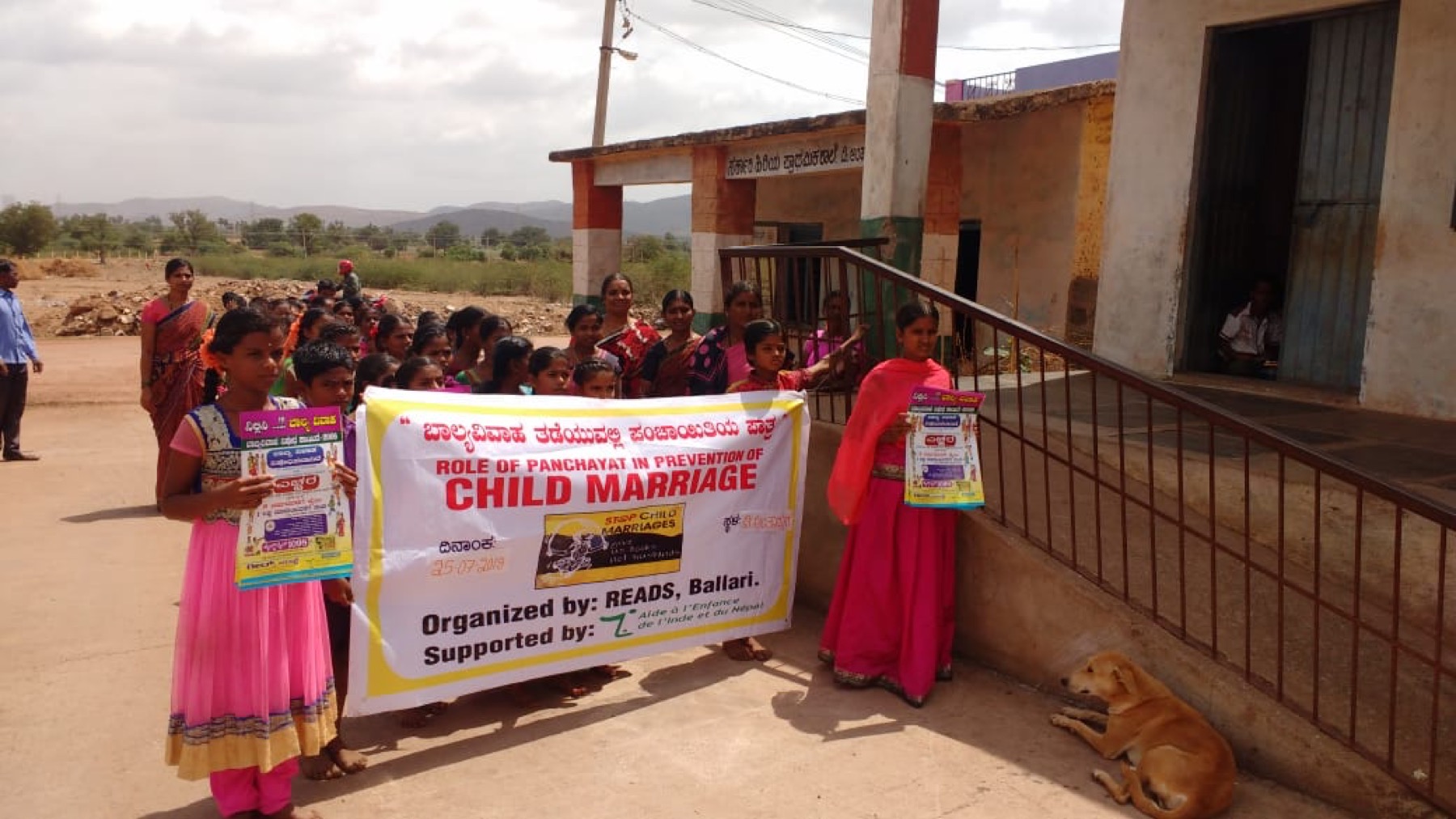 Girls holding a banner on the Panchayat's role in preventing child marriage