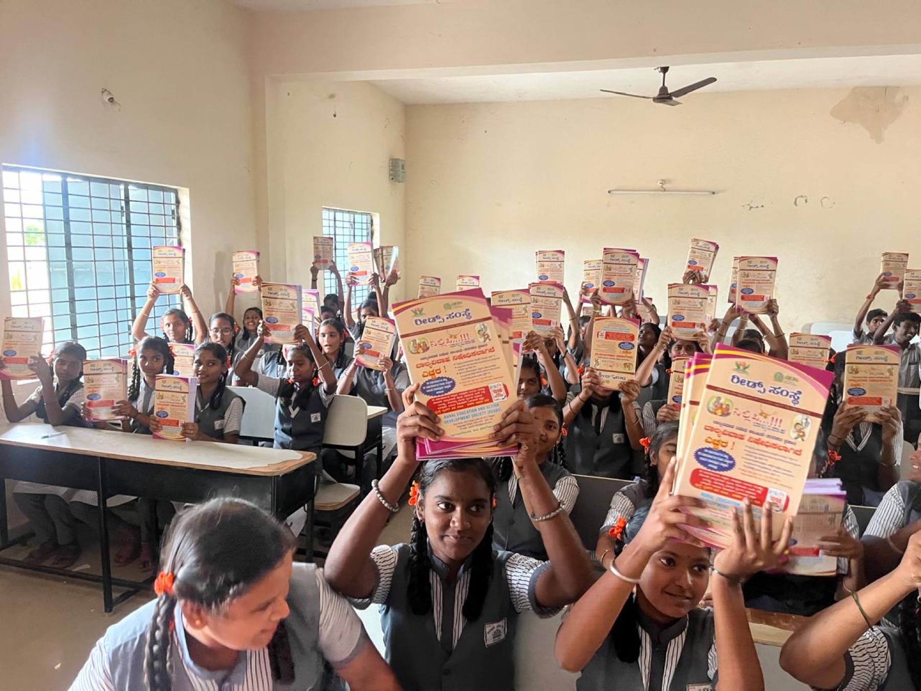 Students holding up READS awareness pamphlets in a classroom
